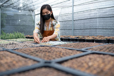 Young woman wearing mask working at botanical garden