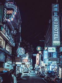 Illuminated street amidst buildings in city at night