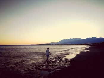 Silhouette man standing on beach against clear sky