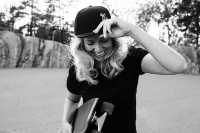 Portrait of a skater girl laughing holding her cap at sunset