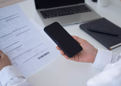 Midsection of man holding smart phone on table
