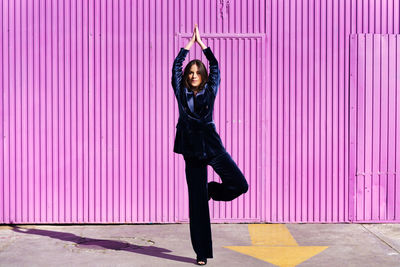 Full length of woman standing on pink wall