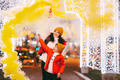 Mom and her son hold colored smoke bombs in their hands during the celebration of christmas 