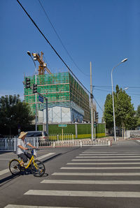 Man riding bicycle on road against sky