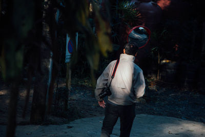 Rear view of man with digital camera standing on street