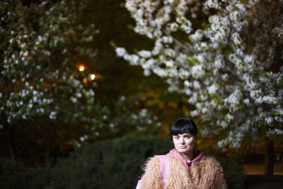 Portrait of young woman standing against trees