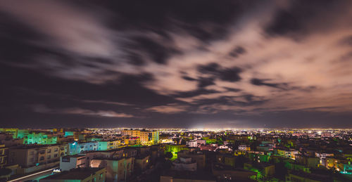 Illuminated cityscape against sky at sunset