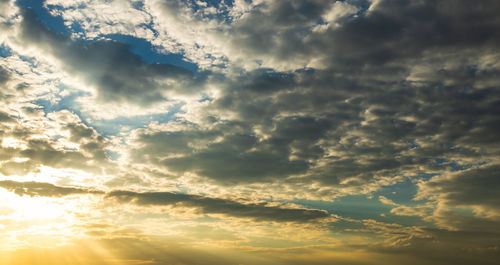 Low angle view of sunlight streaming through clouds