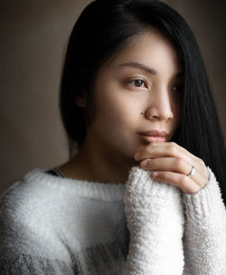 Portrait of young woman looking away against black background