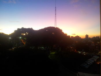 Illuminated trees against sky at sunset