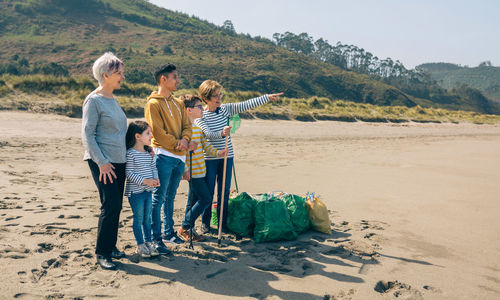 Grandmother pointing away to family at beach