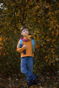 Full length of boy standing on leaves during autumn