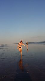 Happy women on beach against clear sky