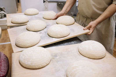 Male chef carrying bread dough on wooden plank in bakery