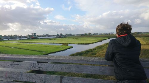 Rear view of woman looking at field against sky