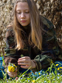 Teenager caucasian girl picking up flowers in springtime in a garden outdoors a sunny day