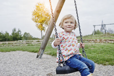 Smiling girl on swing on playground