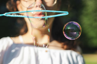 Blurred background of a teenage girl blowing soap bubbles in the park.