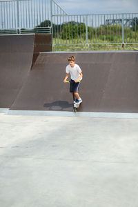 Active ten year old boy riding a scooter in the summer skate park