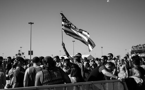 Group of people at flags against clear sky