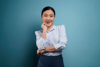 Portrait of a smiling young woman against blue background