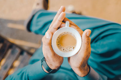 Low section of man holding coffee cup