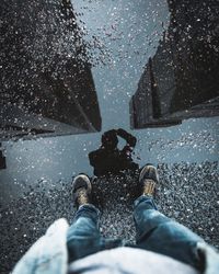 Low section of man standing by puddle in street