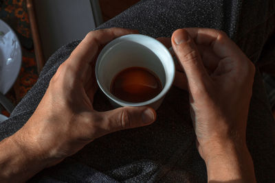 Close-up of hand holding coffee cup on table