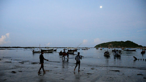 People on beach against sky at dusk