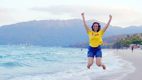 Full length of man with arms outstretched standing at beach