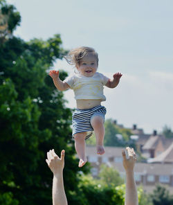 Full length of cute toddler jumping against sky