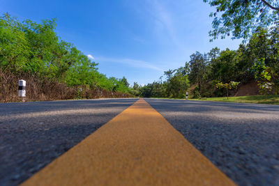 Empty road amidst trees against sky