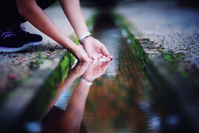 Low section of woman holding water in canal