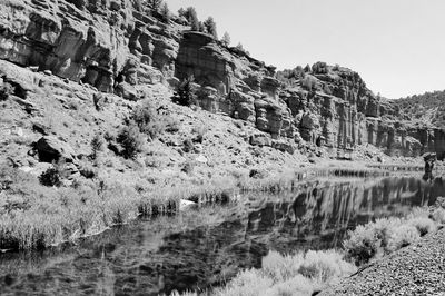 Scenic view of river by rocky mountains against clear sky