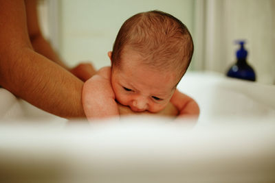 Cropped mother holding newborn in bathtub
