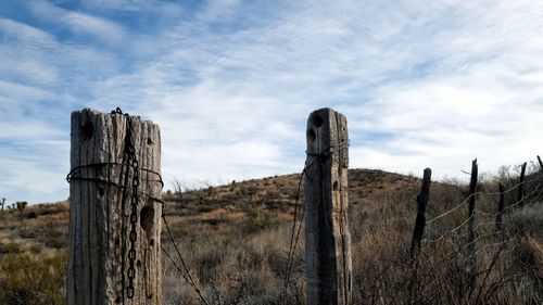 Wooden posts on field against sky