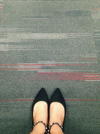 Low section of woman standing on gray carpet