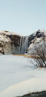Scenic view of waterfall against clear sky during winter