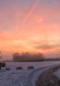 Scenic view of frozen lake against sky during sunset