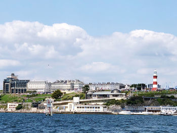 Sea by buildings against sky in city
