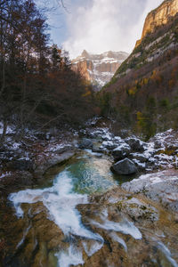 Stream flowing through rocks against sky