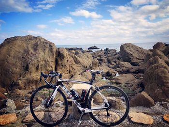 Bicycles on rock by sea against sky