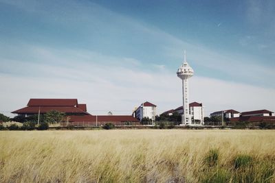 Houses on field by buildings against sky