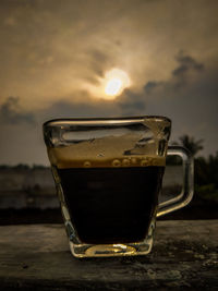 Close-up of coffee on table against sunset