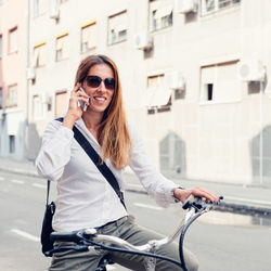 Woman talking over smart phone while riding bicycle on road