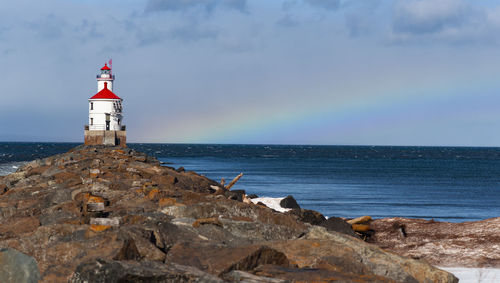 Lighthouse by sea against sky