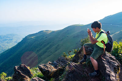 Side view of woman sitting on mountain