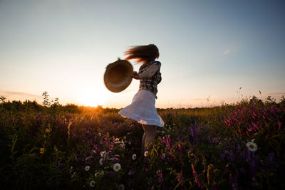Woman standing on field at sunset