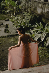 Rear view of woman wearing dress while standing in yard