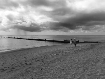 Scenic view of beach against cloudy sky